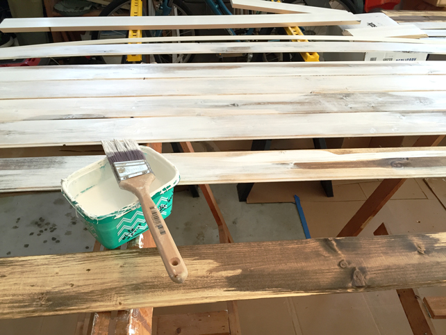 Dark stained wood planks are getting a wash of white paint prior to sanding