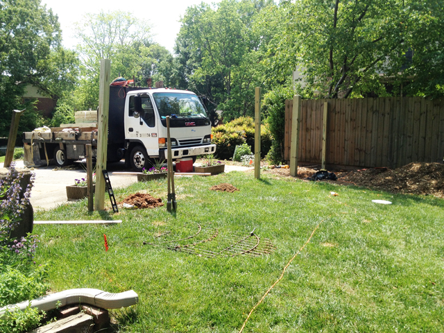 Yard area just in front of driveway is being prepared for installing of a picket fence. A string is laid out to note post holes.