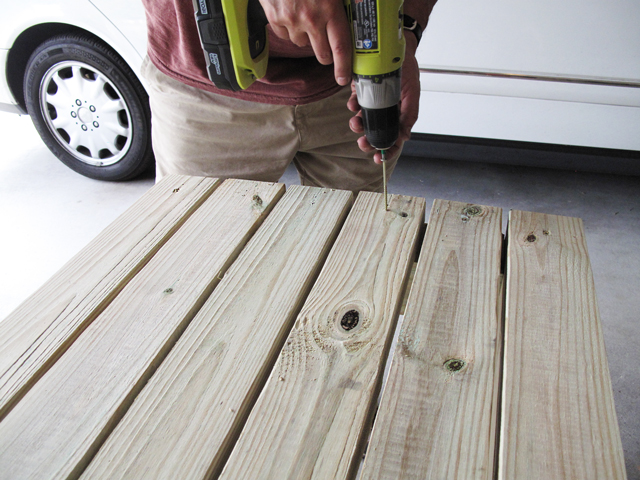 drilling screws into two-by-fours to attach top of rain barrel stand