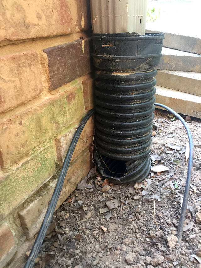 closeup view of hole in flexible pipe at ground level