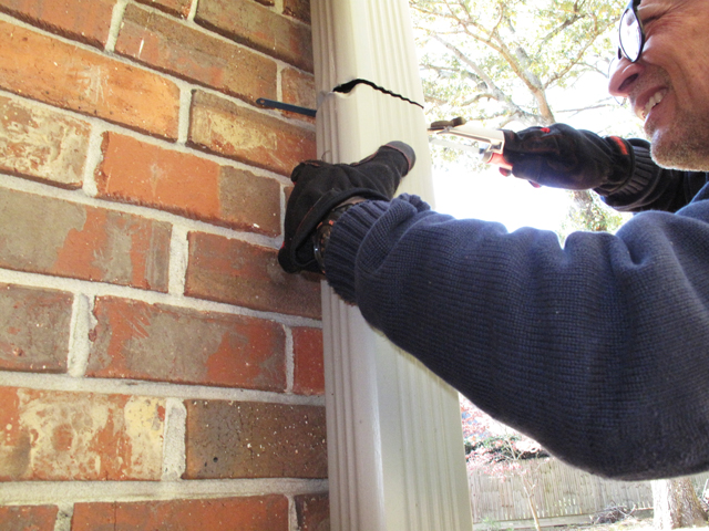 Man continues to saw the remainder of the downspout in order to remove the section in order to install the downspout diverter