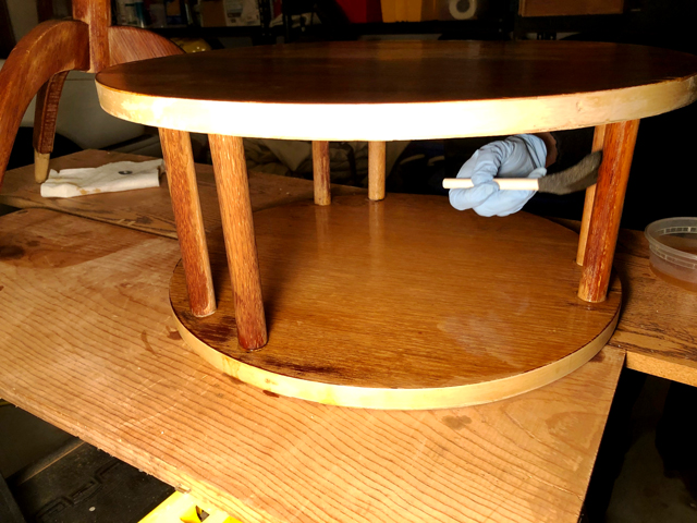 Bleach solution is applied with a sponge to wood supports between table shelves