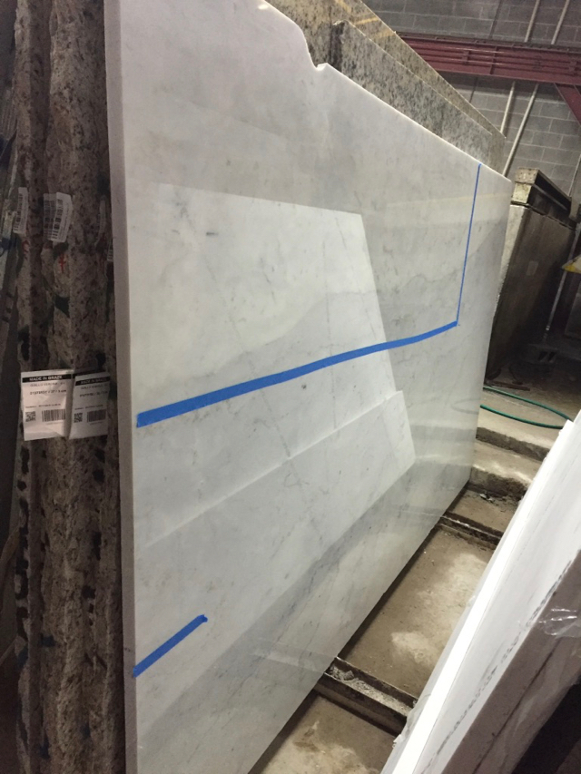 Large slab of white marble is marked with tape to indicate where cuts are to be made