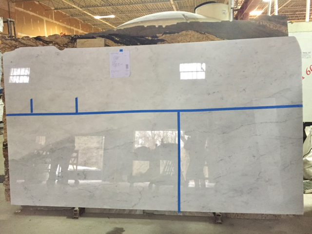 Large slab of white marble is marked with tape to indicate where cuts are to be made