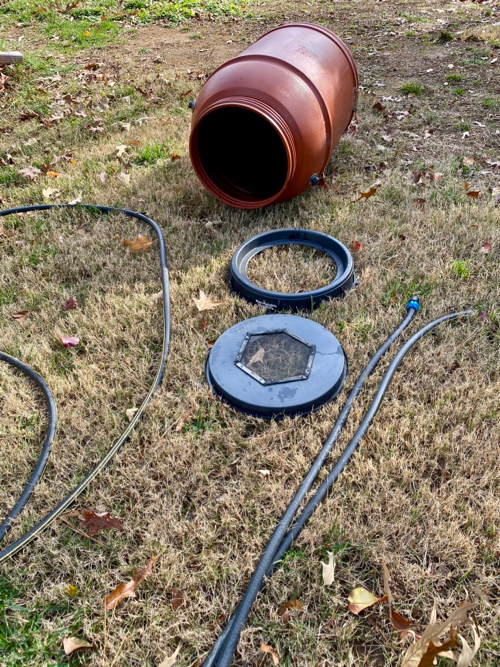 Rain barrel lying on side, showing disconnected 2-piece lid and hose