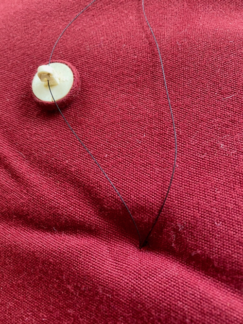 thread with button connected laying on pillow