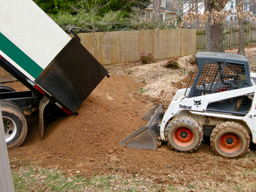  truck dumps soil and Bobcat equipment spreads around yard