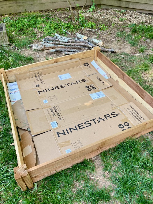 cardboard laid inside wood frame of raised bed