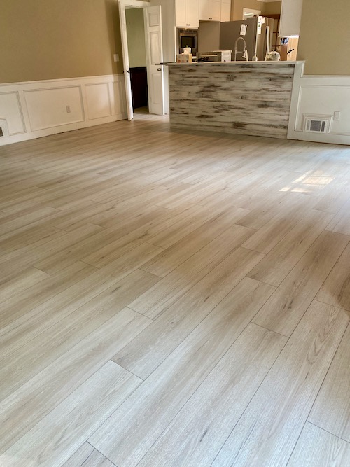 New white and grey colored, wide planked flooring is installed in large family room 
