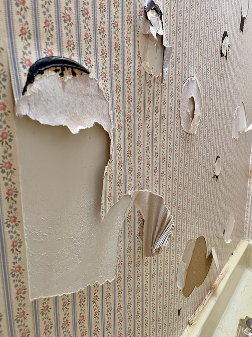 a close up photo of holes left in wallpaper when glued section of mirror was released from wall
