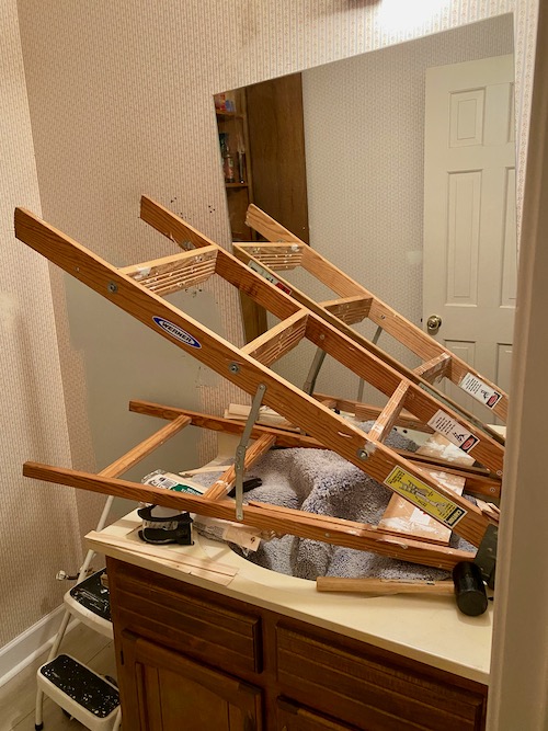 step ladder is laid on its side in front of mirror in order to secure mirror when it releases from the wall